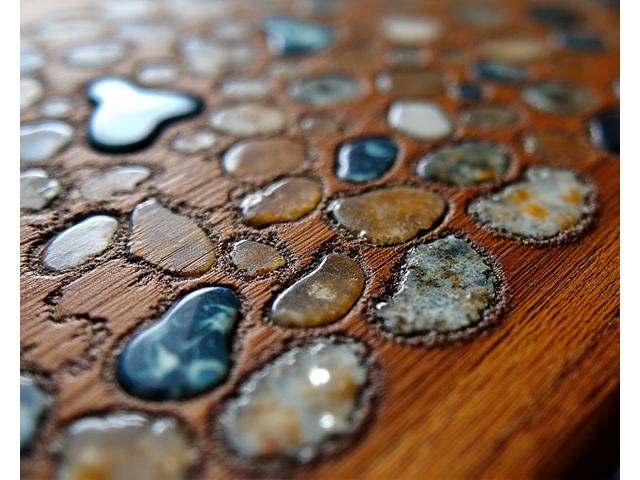 Gros plan sur une marqueterie de pierre complexe et détaillée sur une surface en bois.